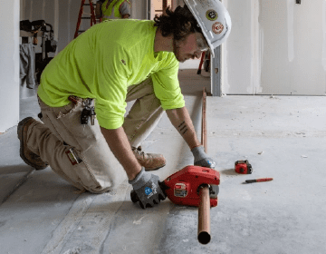 plumbing technician installing piping in multi-unit residential building