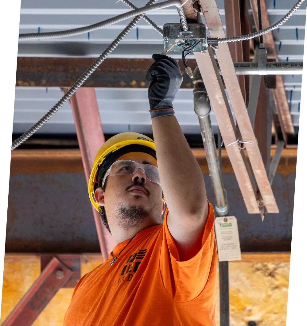 Electrical technician installing lighting and wiring in a new commercial warehouse