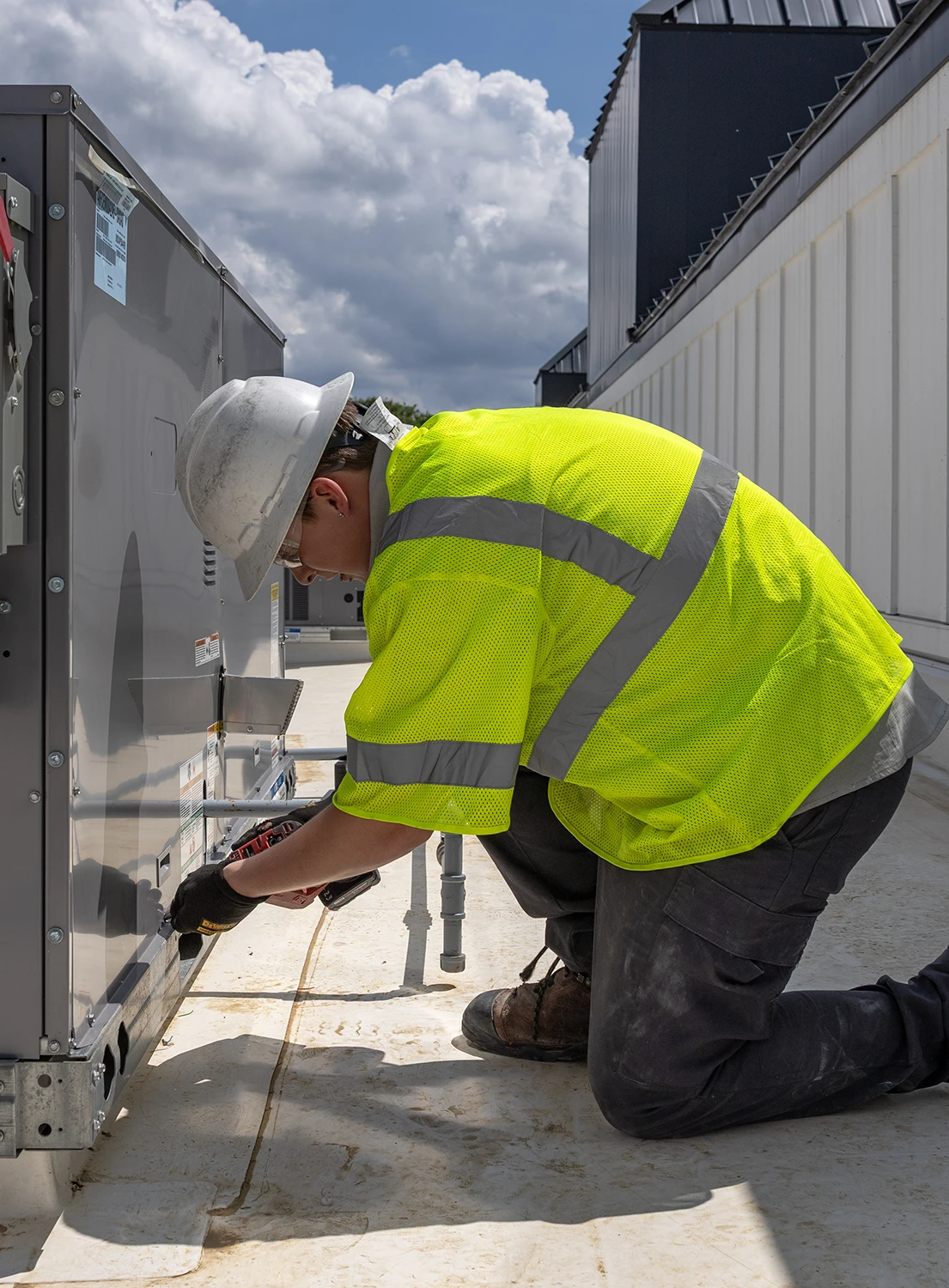 Commercial HVAC technician servicing rooftop HVAC unit on commercial building